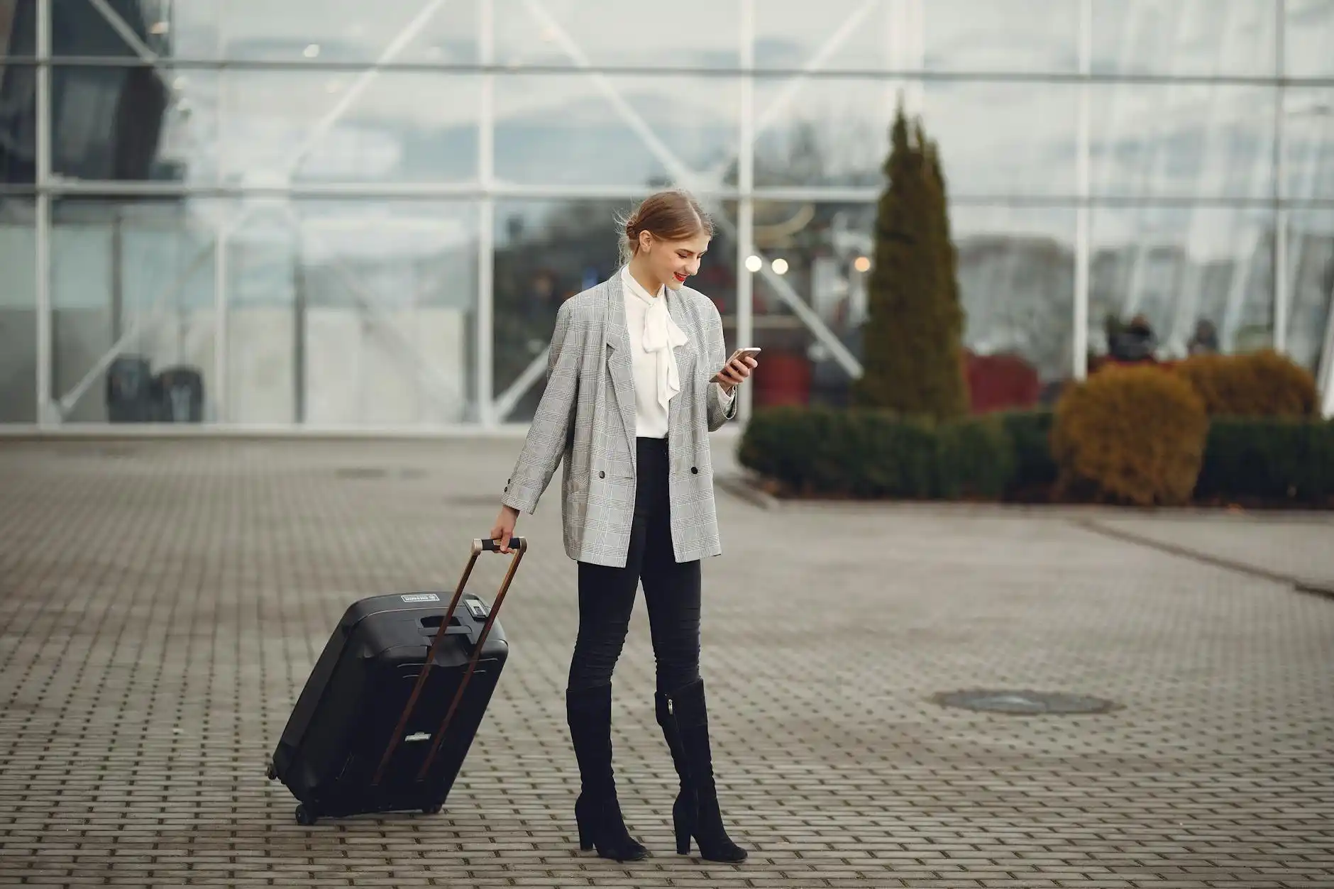 close-up of chauffeur loading suitcases into a black luxury SUV outside Sea-Tac arrivals while travelers review booking confirmation on smartphone