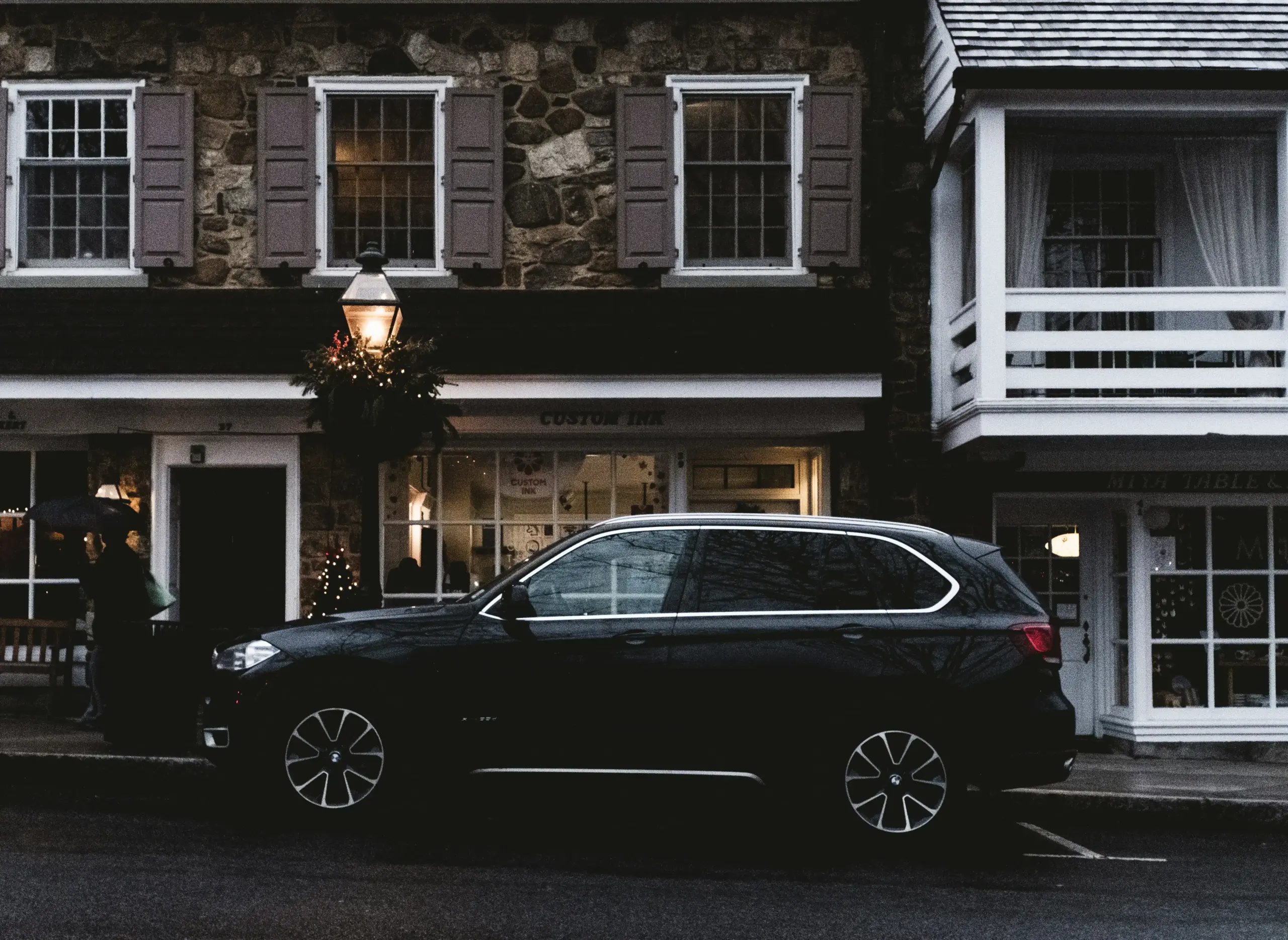 comparison scene showing a black luxury sedan and a premium black SUV parked side by side outside a modern Seattle hotel, suitcases arranged to show capacity differences, rainy ...