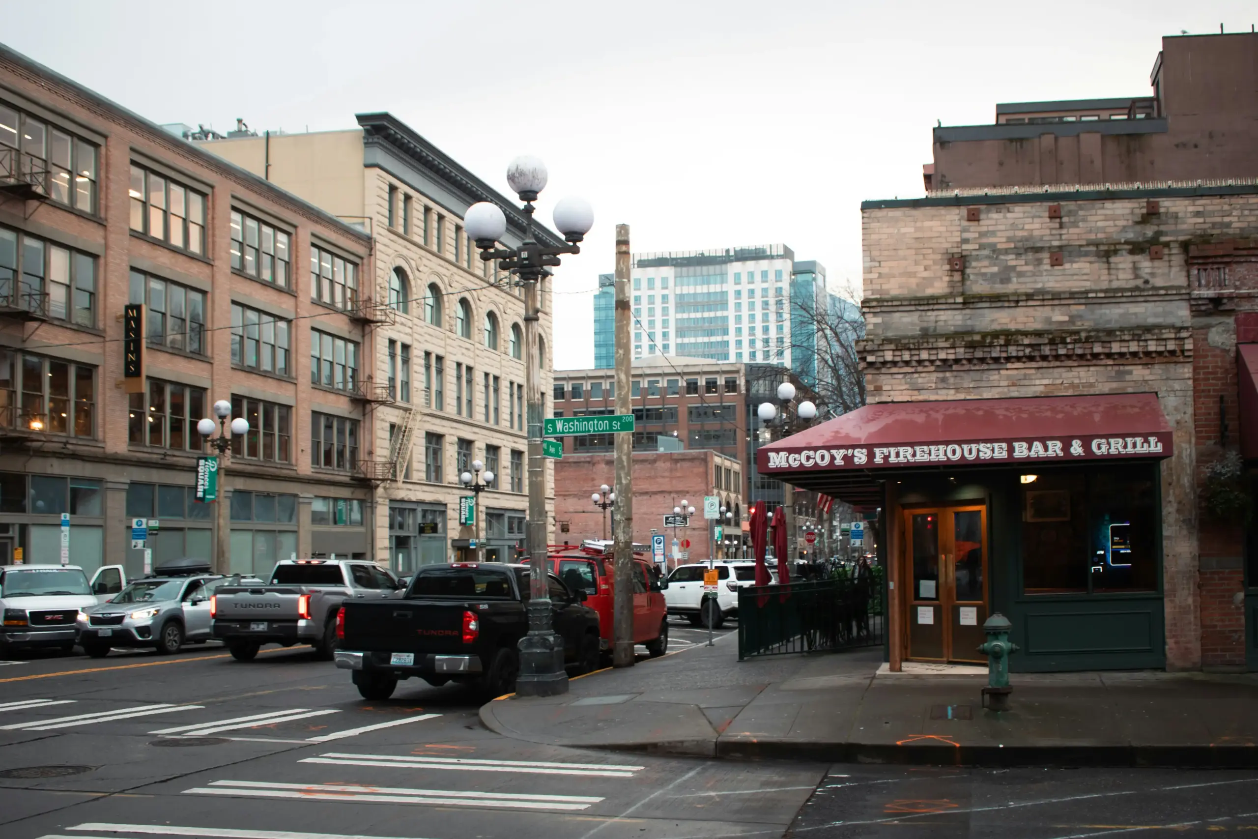 black luxury SUV driving carefully on a rain-slick Seattle street at dusk, headlights reflecting on pavement, Space Needle visible in background, safe following distance in traffic
