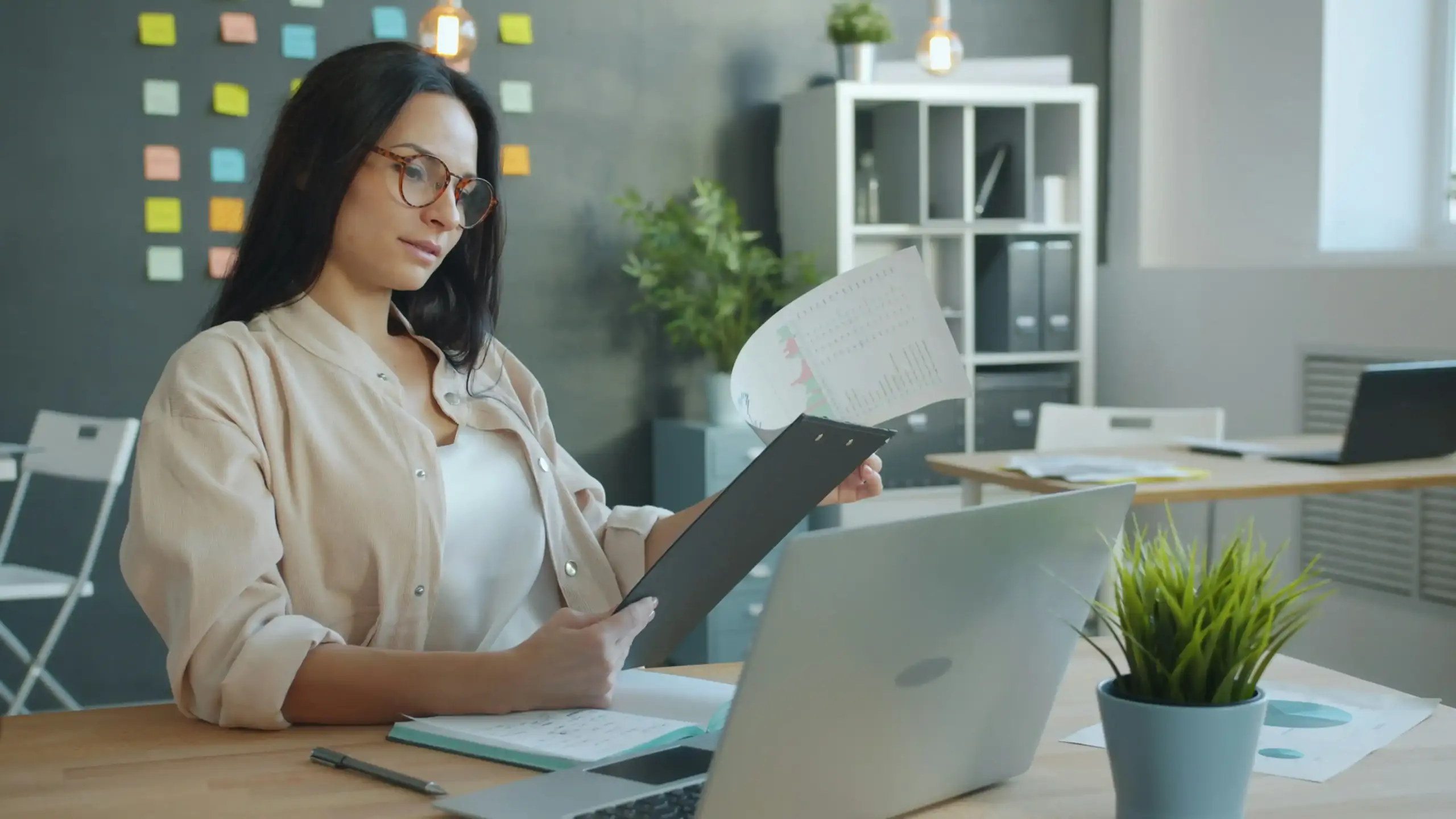 finance manager at a modern Seattle office reviewing centralized transportation invoices on a laptop, with a calendar, corporate credit card, and skyline view through large windows