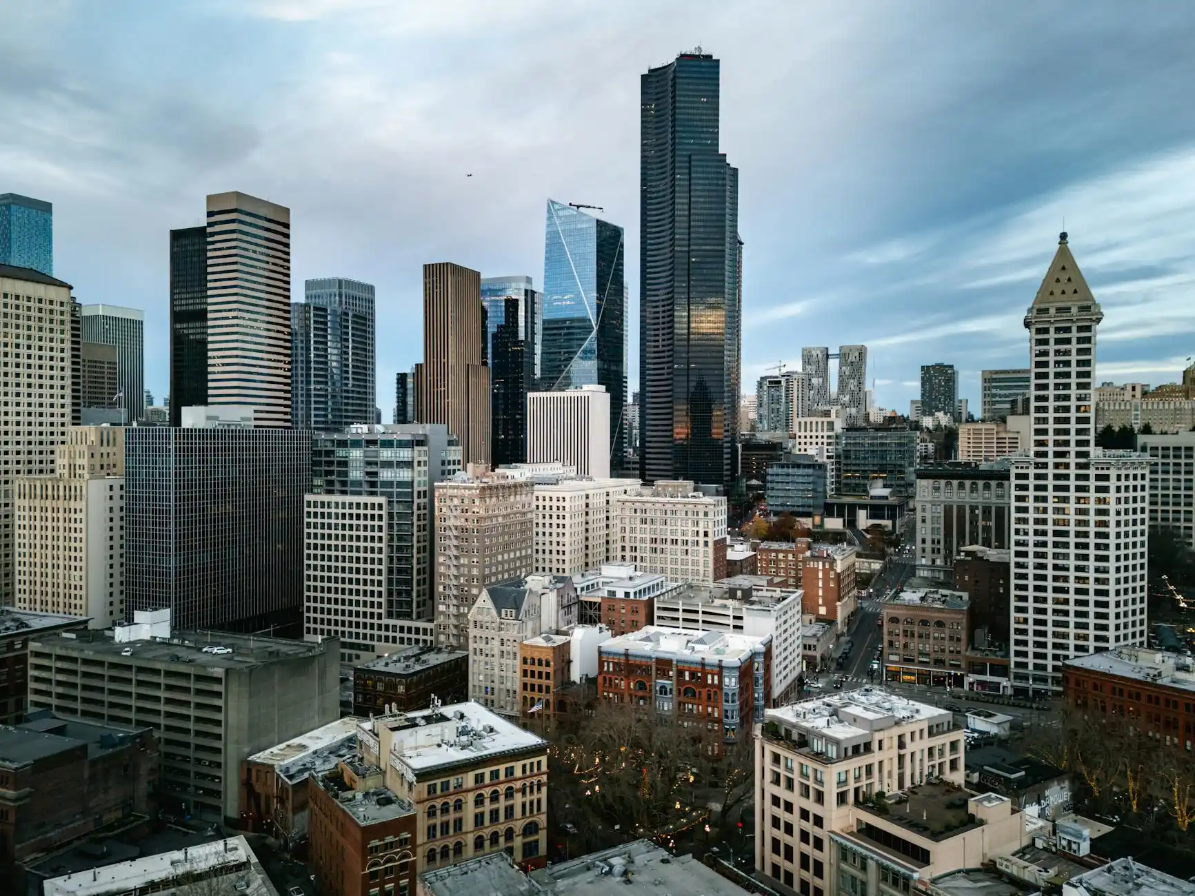 sleek black executive shuttle bus parked in front of a modern downtown Seattle office tower at sunrise, business travelers in suits boarding with carry-on luggage, city skyline ...