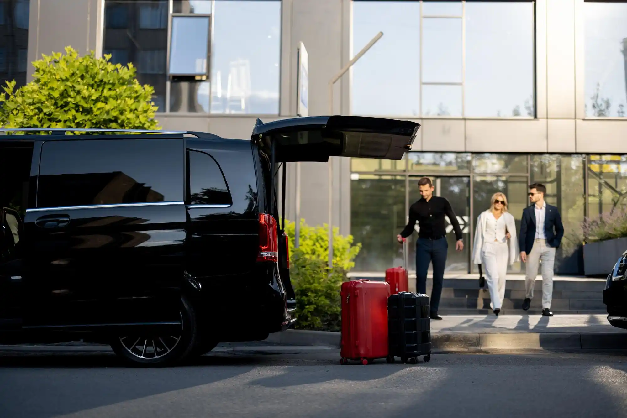 executive group transportation comparison scene in Seattle, multiple black SUVs in traffic on one side and a luxury executive minibus using a hotel loading zone on the other, ra...