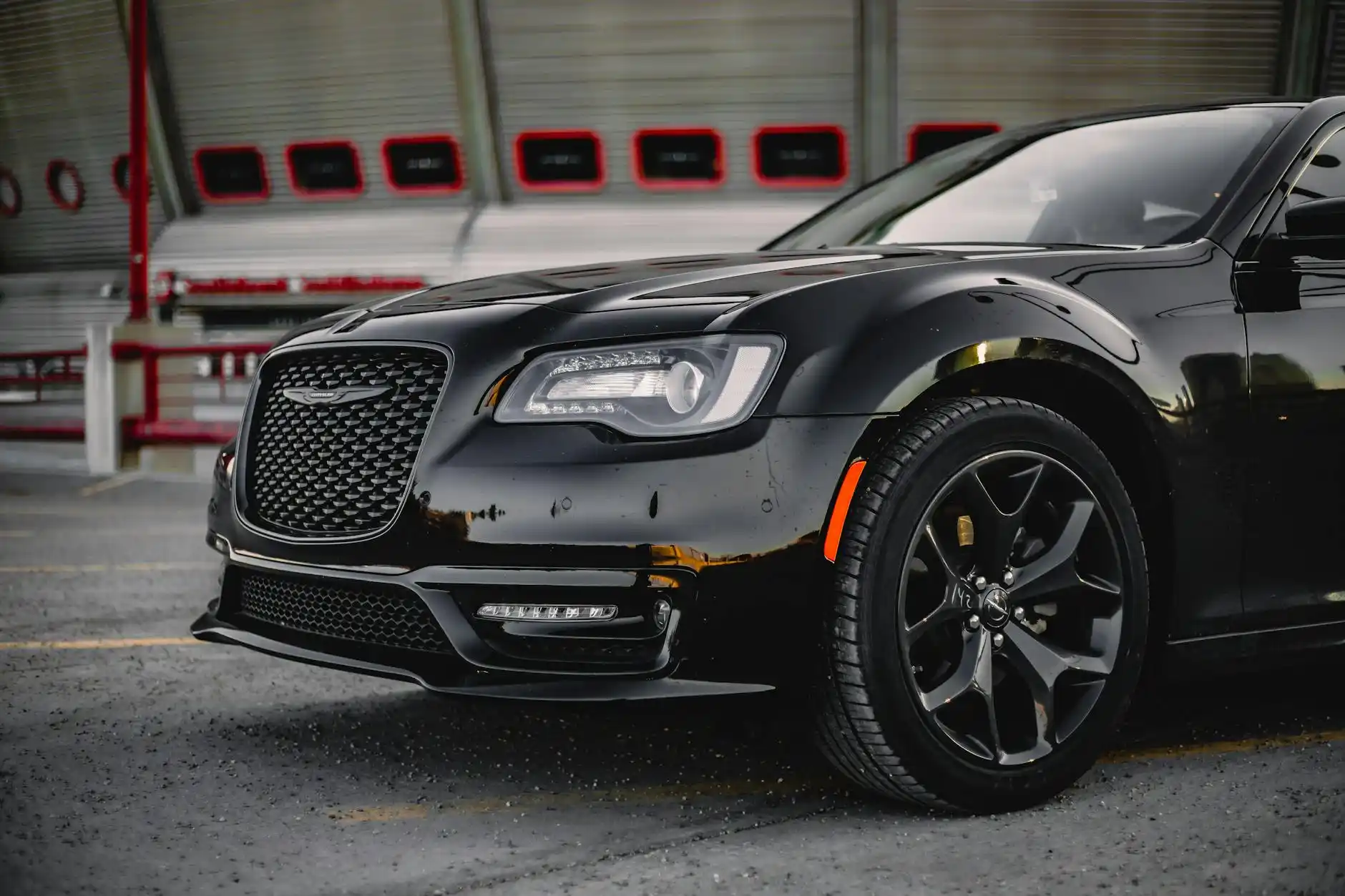 black luxury town car parked at Paine Field terminal curb during golden hour, traveler with rolling suitcase approaching driver in suit, modern regional airport background