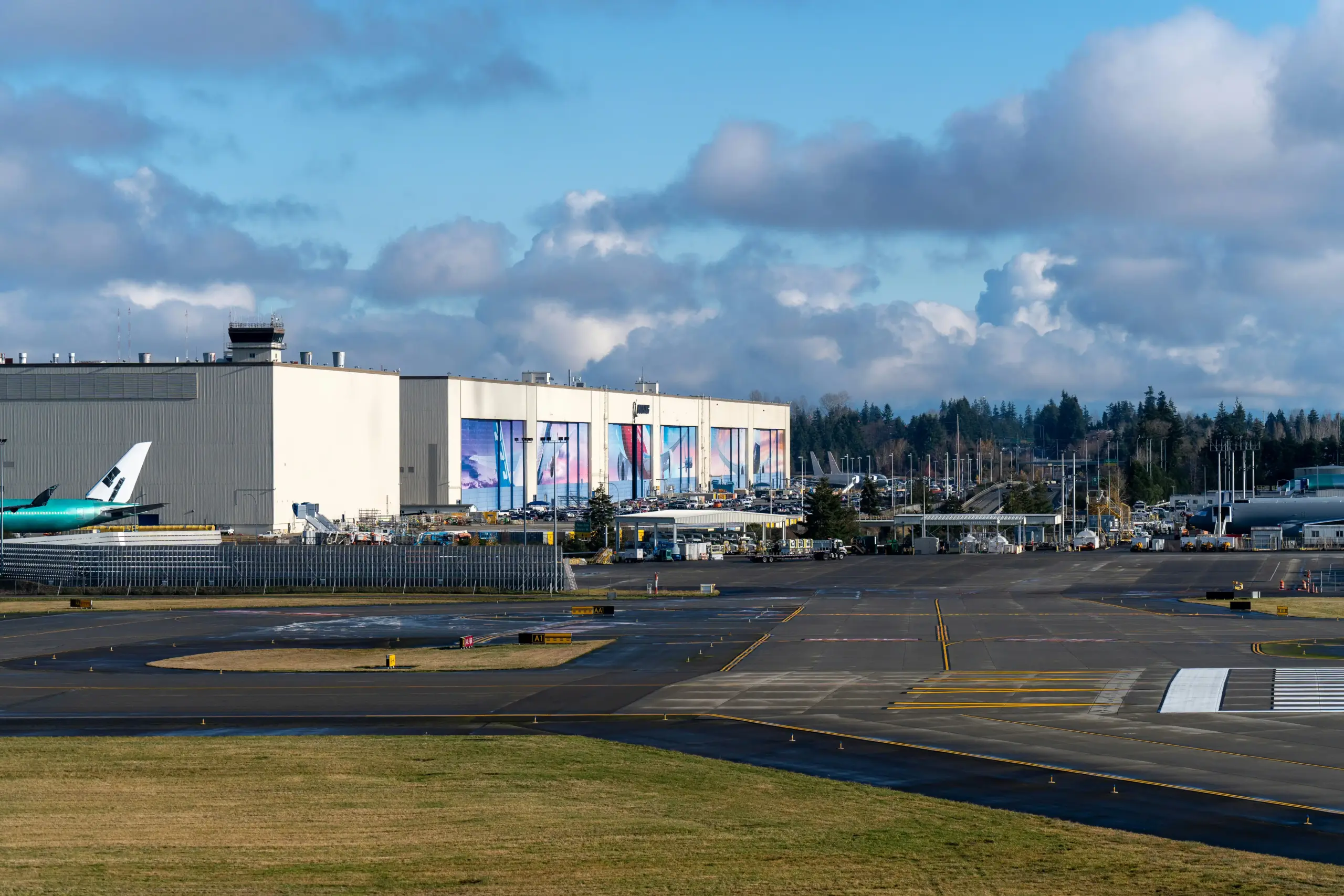 aerial view of Paine Field airport terminal and surrounding Everett area with sleek black SUV on nearby road, clear Pacific Northwest morning light
