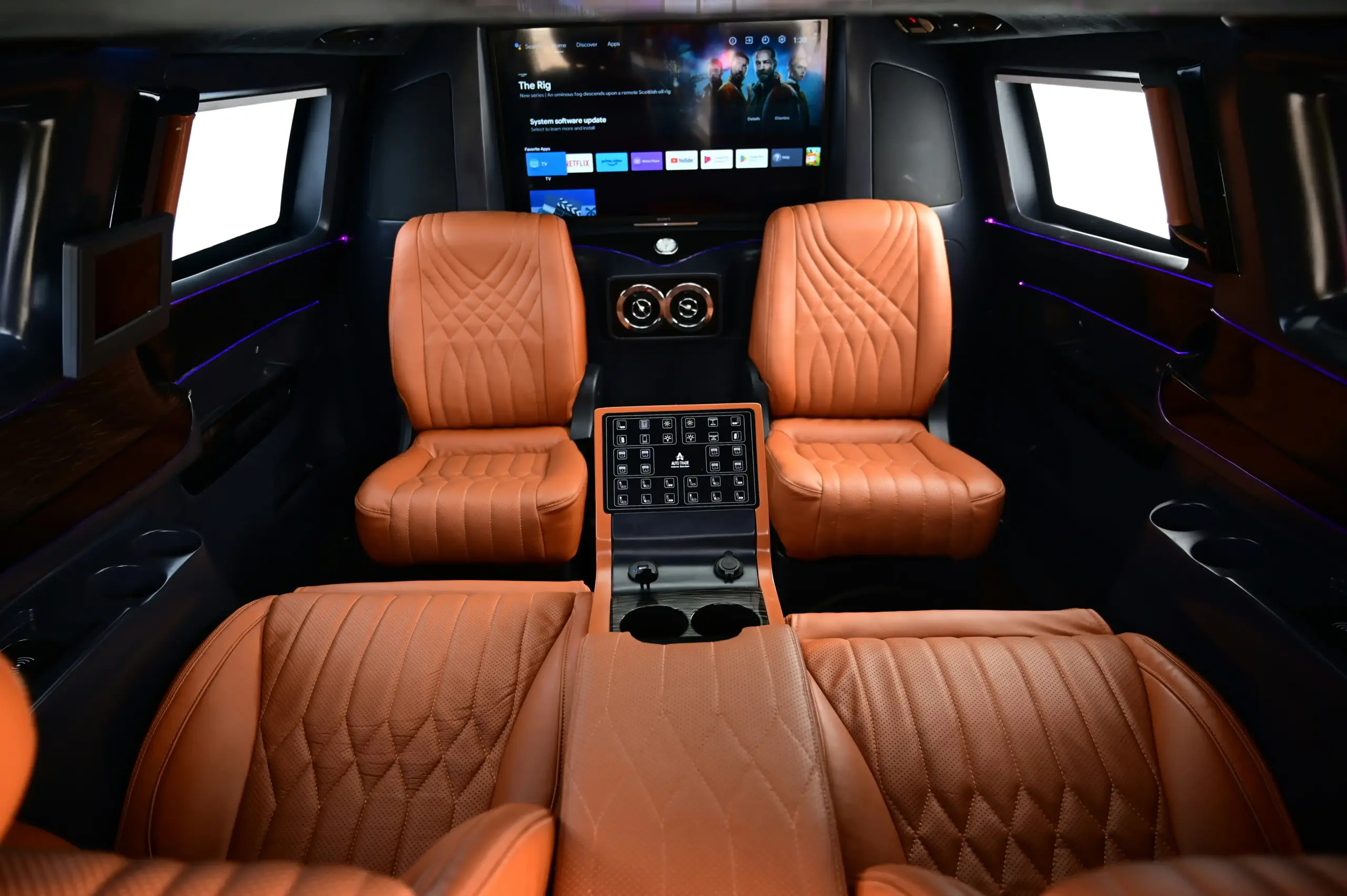upscale black SUV interior with tan leather seats, neatly placed carry-on luggage, bottled water, and soft natural light through tinted windows
