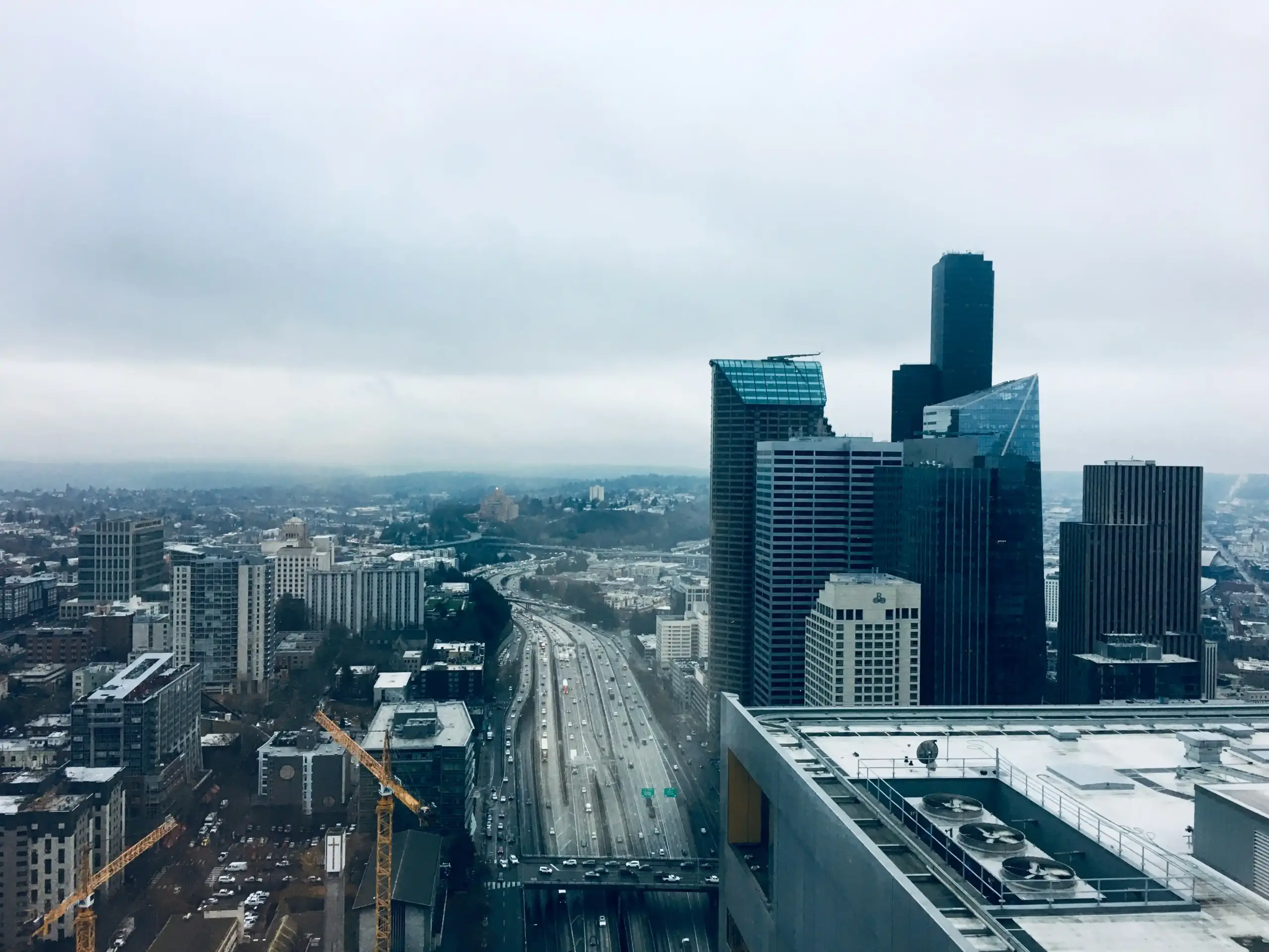 aerial view of Interstate 5 between SeaTac and downtown Seattle during rush hour, dense northbound traffic, overcast sky, city towers rising ahead