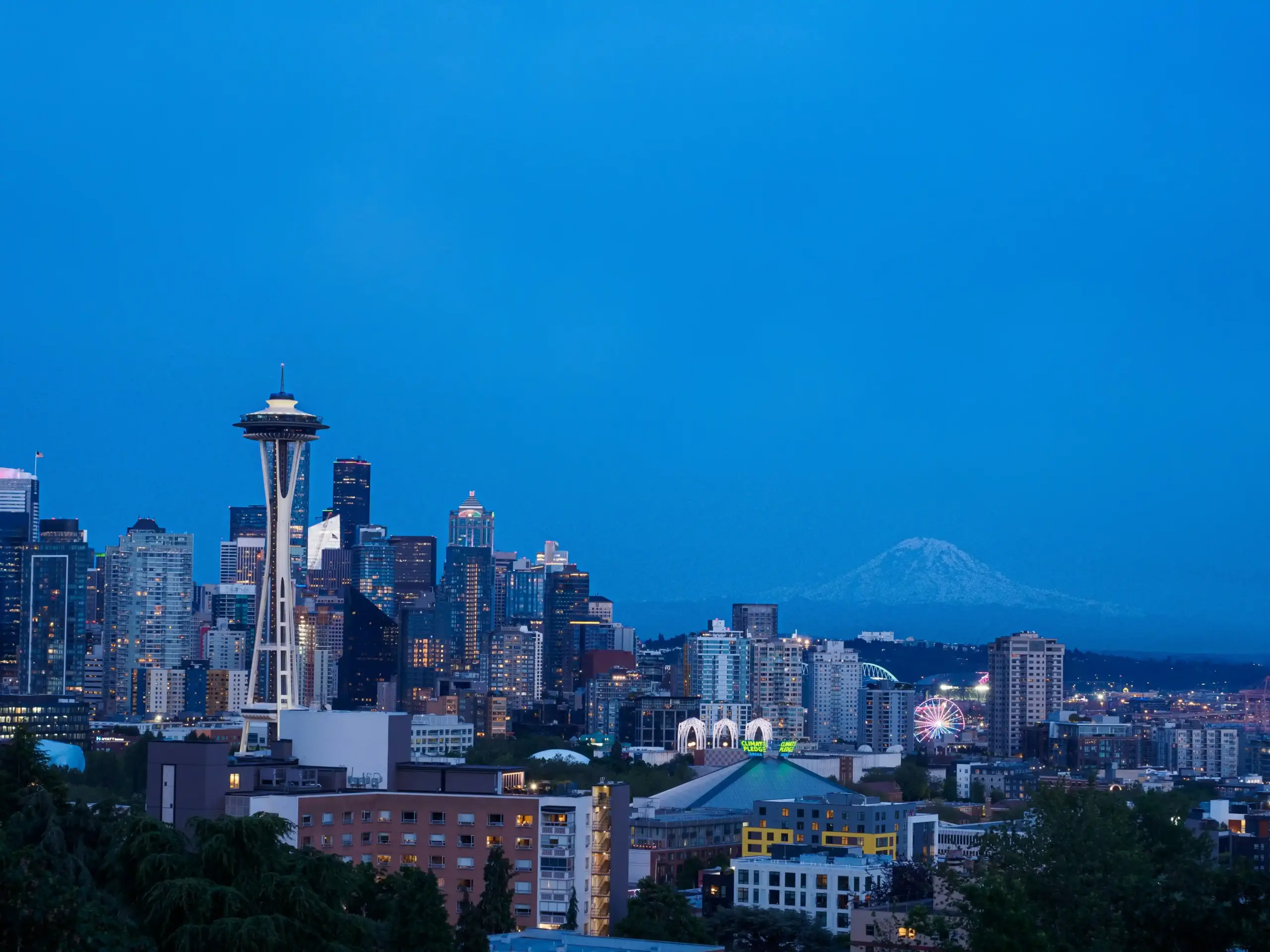 upscale hotel entrance in Seattle at dusk, chauffeur opening rear door for visiting executive couple, warm lobby lighting, concierge nearby, premium black vehicle at curb