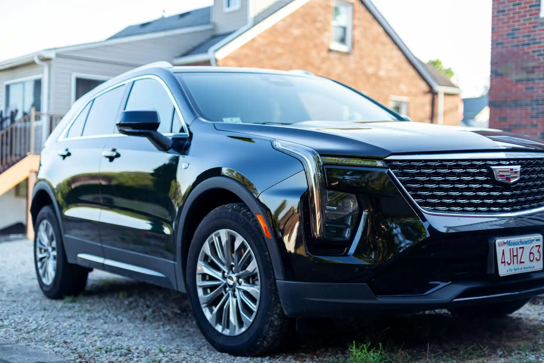 black luxury SUV parked outside a modern Woodinville winery at golden hour, vineyard rows in the background, elegantly dressed couple stepping out with wine barrels and warm Pac...