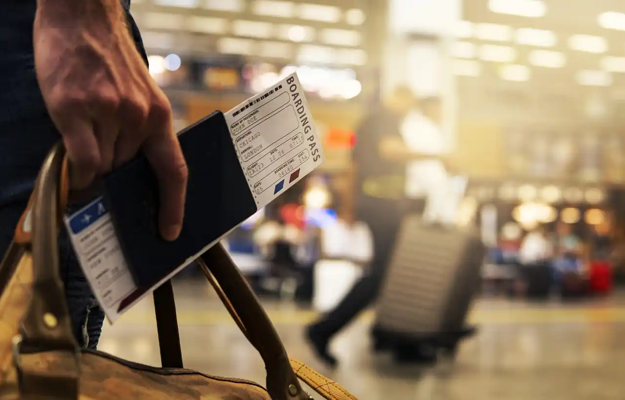 smartphone displaying confirmed airport car reservation next to passport, boarding pass, luxury car keys, and coffee on a modern Seattle hotel desk