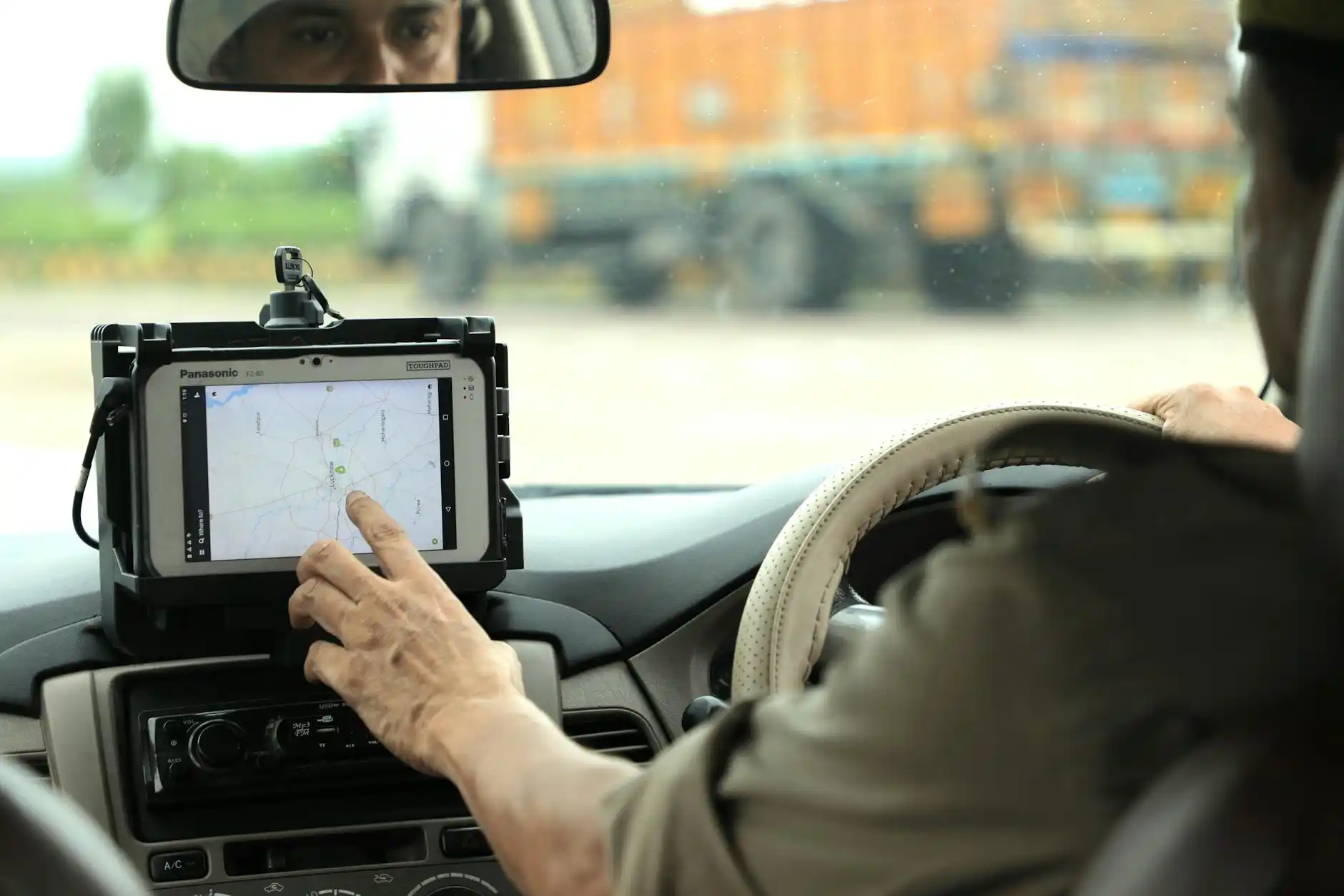 close-up of a chauffeur’s reservation tablet showing pickup details, FBO name, passenger initials, and Seattle map route to Boeing Field, inside a premium leather vehicle