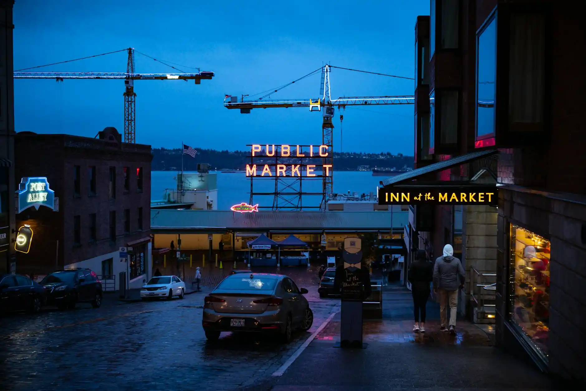 luxury black stretch limousine and executive SUV parked curbside in downtown Seattle near Pike Place Market at golden hour, wet streets reflecting city lights, professional chau...