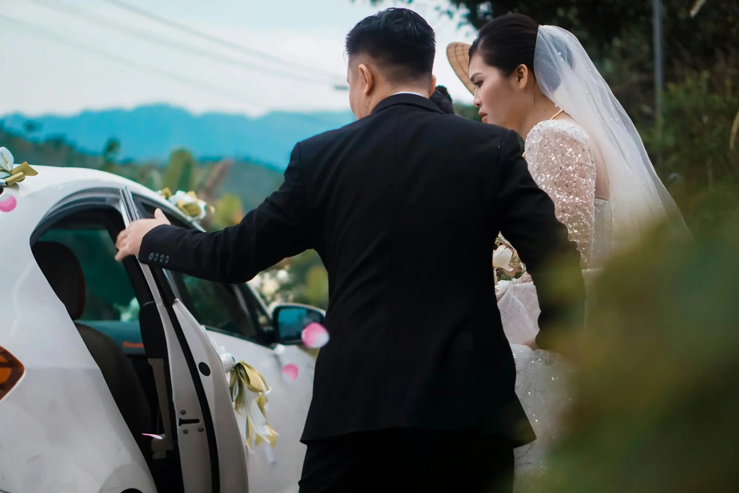 elegant wedding couple entering a white stretch limousine outside a historic Seattle venue with fresh floral arrangements and evening string lights
