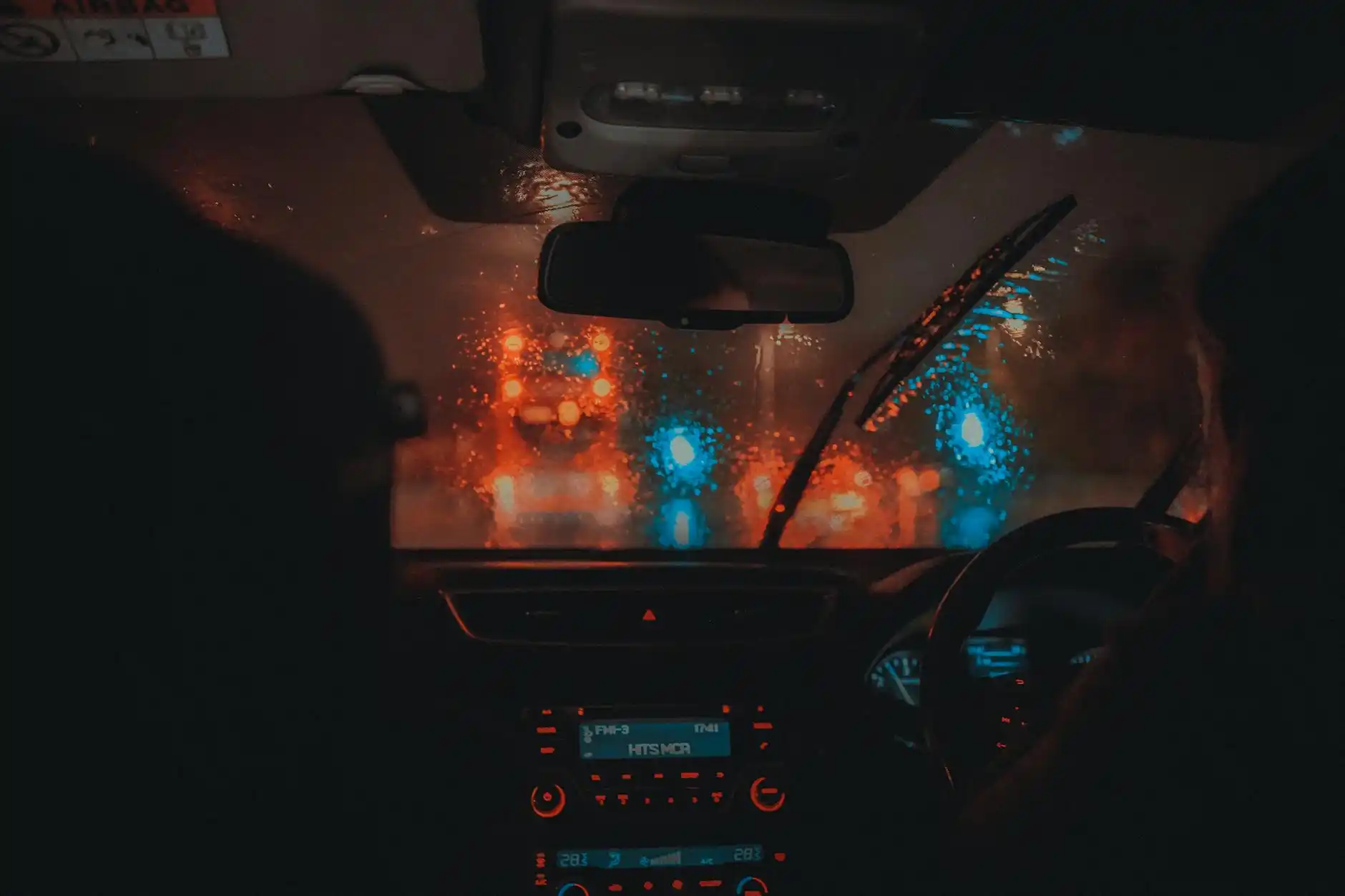 luxury sedan interior with black leather seats, bottled water, soft ambient lighting, and Seattle skyline visible through rain-speckled windows