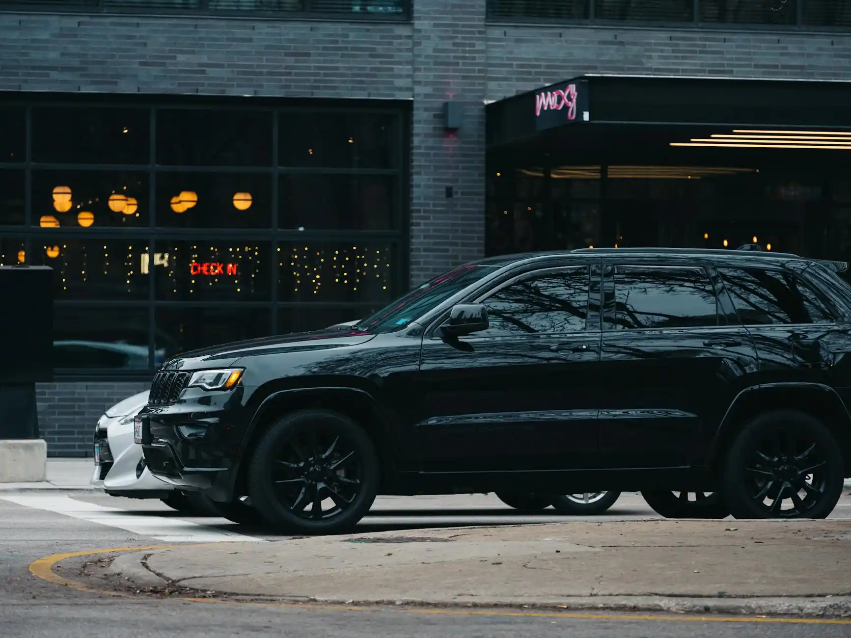 sleek black luxury SUV arriving outside a glass office tower in downtown Seattle at sunrise, chauffeur opening the rear door for a business executive carrying a leather briefcas...