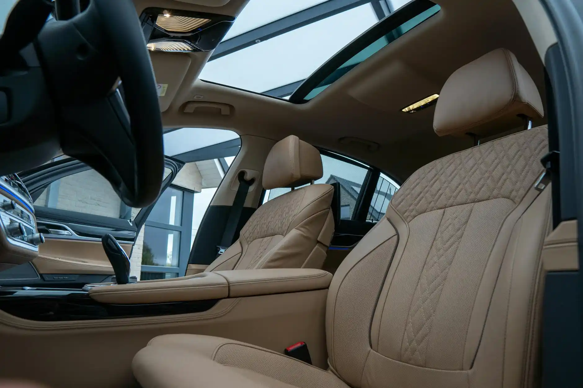 interior of a premium full-size SUV with tan leather captain seats, ambient lighting, bottled water, panoramic roof, and Seattle skyline visible through the windows