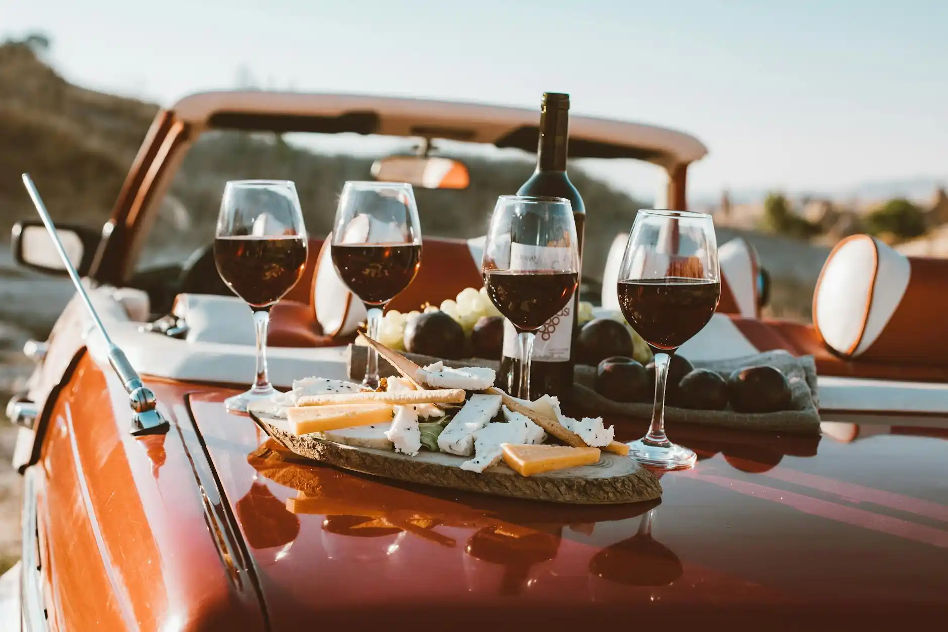 elegant couple entering a luxury chauffeur vehicle at sunset after a day in Woodinville wine country, winery lights glowing softly behind them, bottles carefully placed in the t...