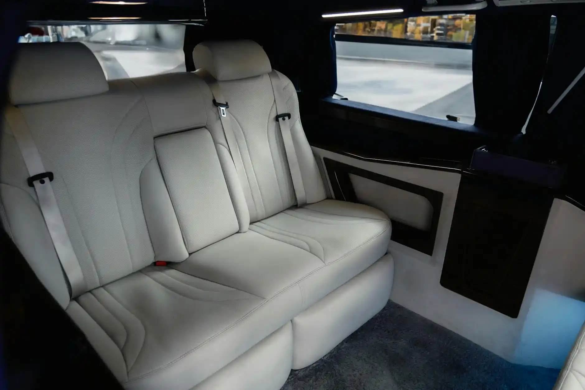 interior of a premium executive SUV with black leather seats, soft ambient lighting, bottled water, city skyline visible through windows, two executives reviewing notes before d...