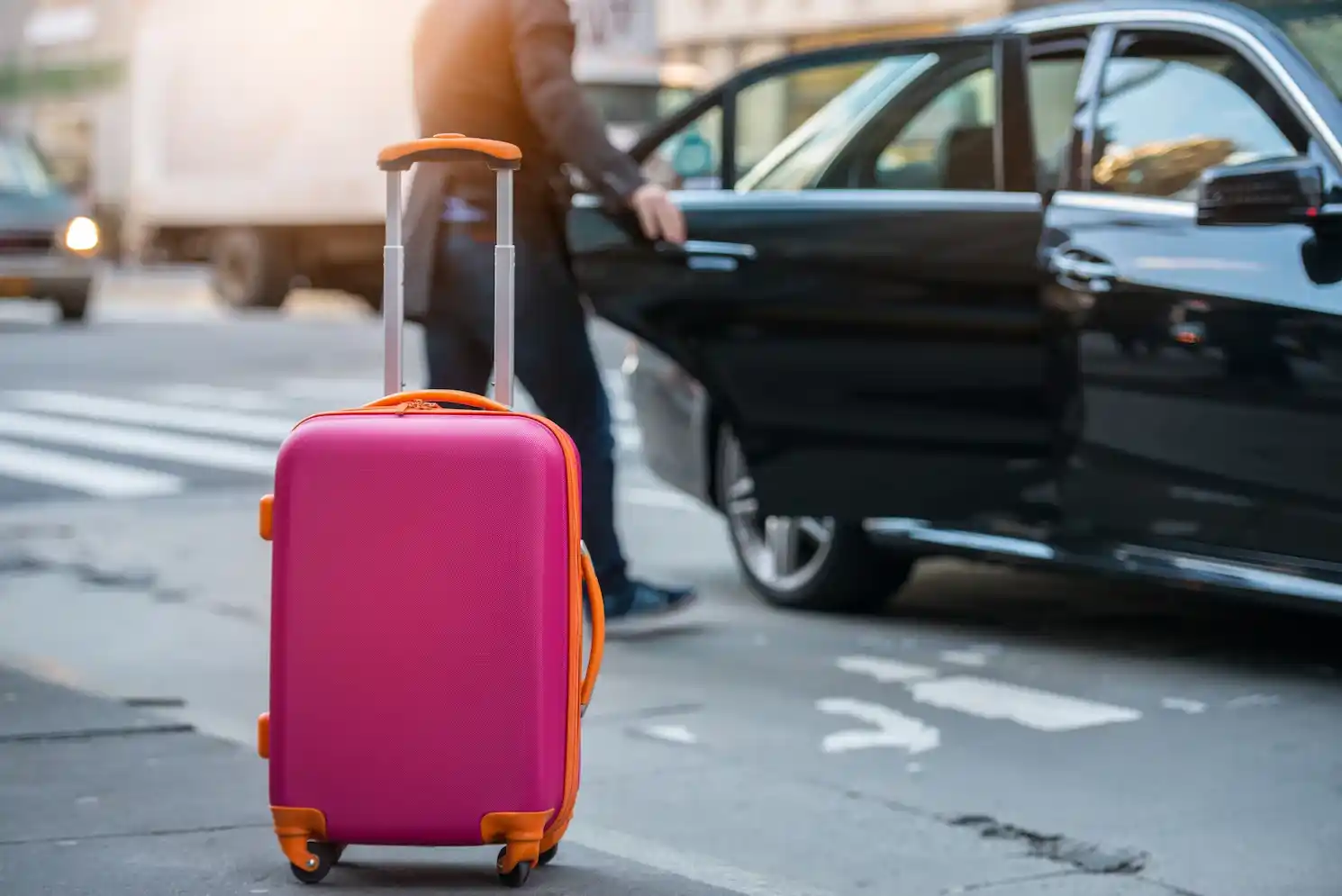 black luxury SUV dropping off travelers with rolling suitcases at the Bellingham ferry terminal entrance on an overcast Pacific Northwest morning, ferry vessel visible in the ba...
