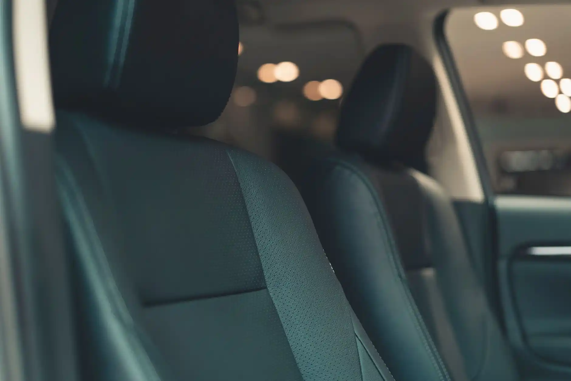 elegant black town car interior with leather seats, soft natural light, a traveler using a phone beside stacked suitcases, and Pacific Northwest scenery outside the window