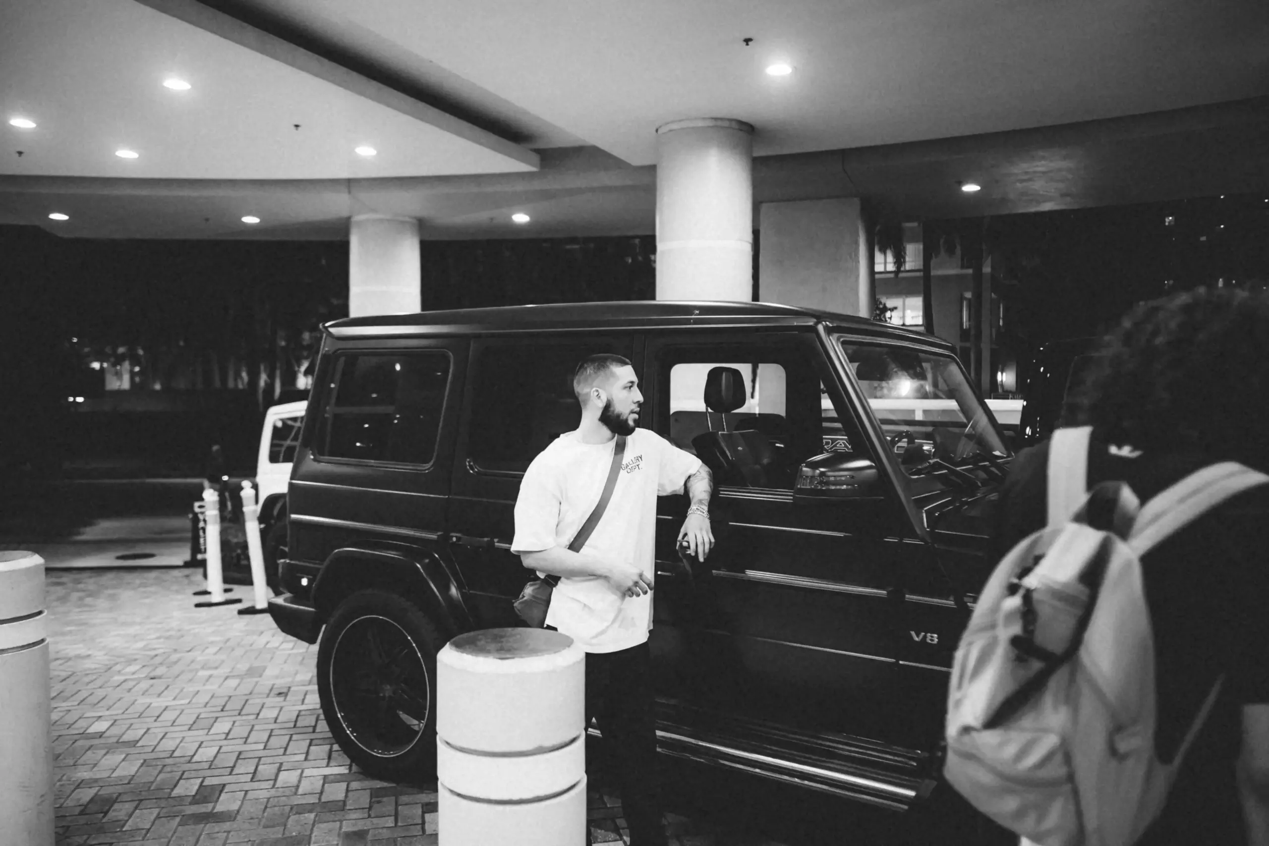 open rear cargo area of a luxury black SUV packed neatly with concert blankets, weekend bags, bottled water, and premium travel accessories at a Seattle hotel entrance