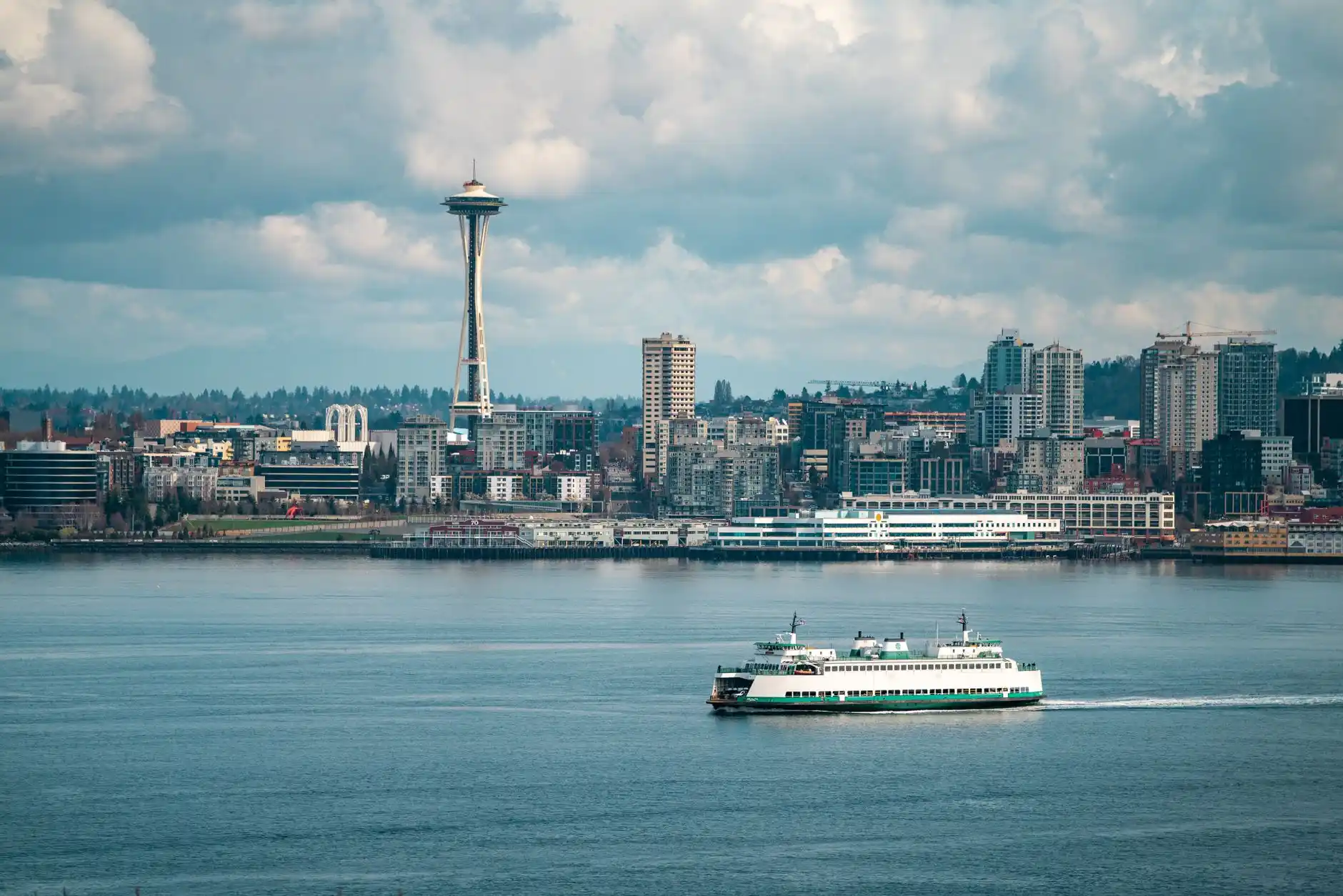 split scene showing live flight tracking screen on smartphone and chauffeur waiting in designated SeaTac pickup zone with luxury sedan, cloudy Seattle skyline in background