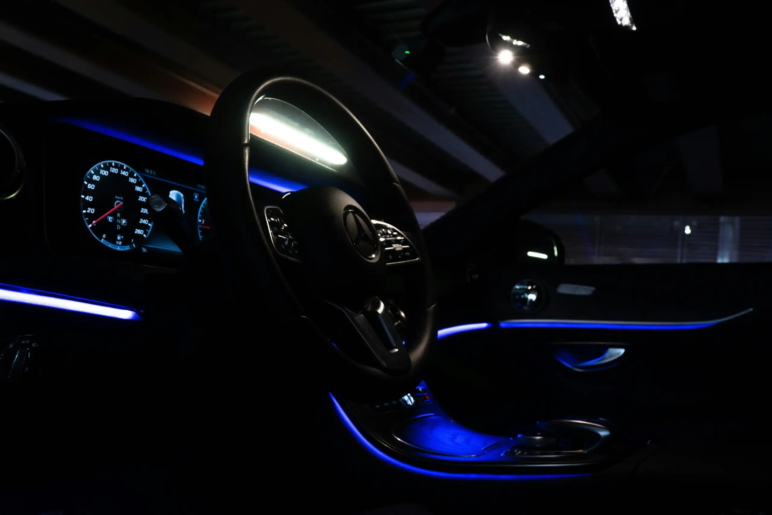 elegant interior of a luxury limousine with tan leather seating, ambient blue lighting, chilled water bottles, and Seattle skyline visible through tinted windows