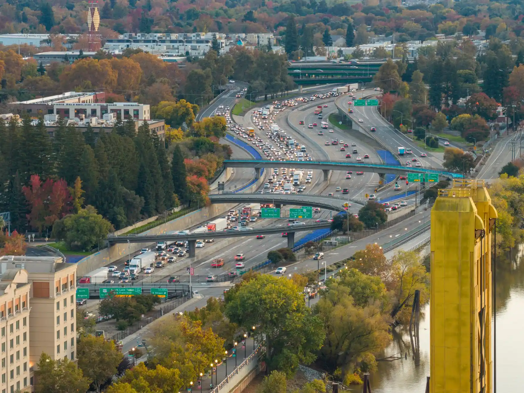 aerial view of Seattle freeway traffic near Sea-Tac during rainy rush hour, glowing brake lights, overcast sky, airport runways visible beyond highway interchanges