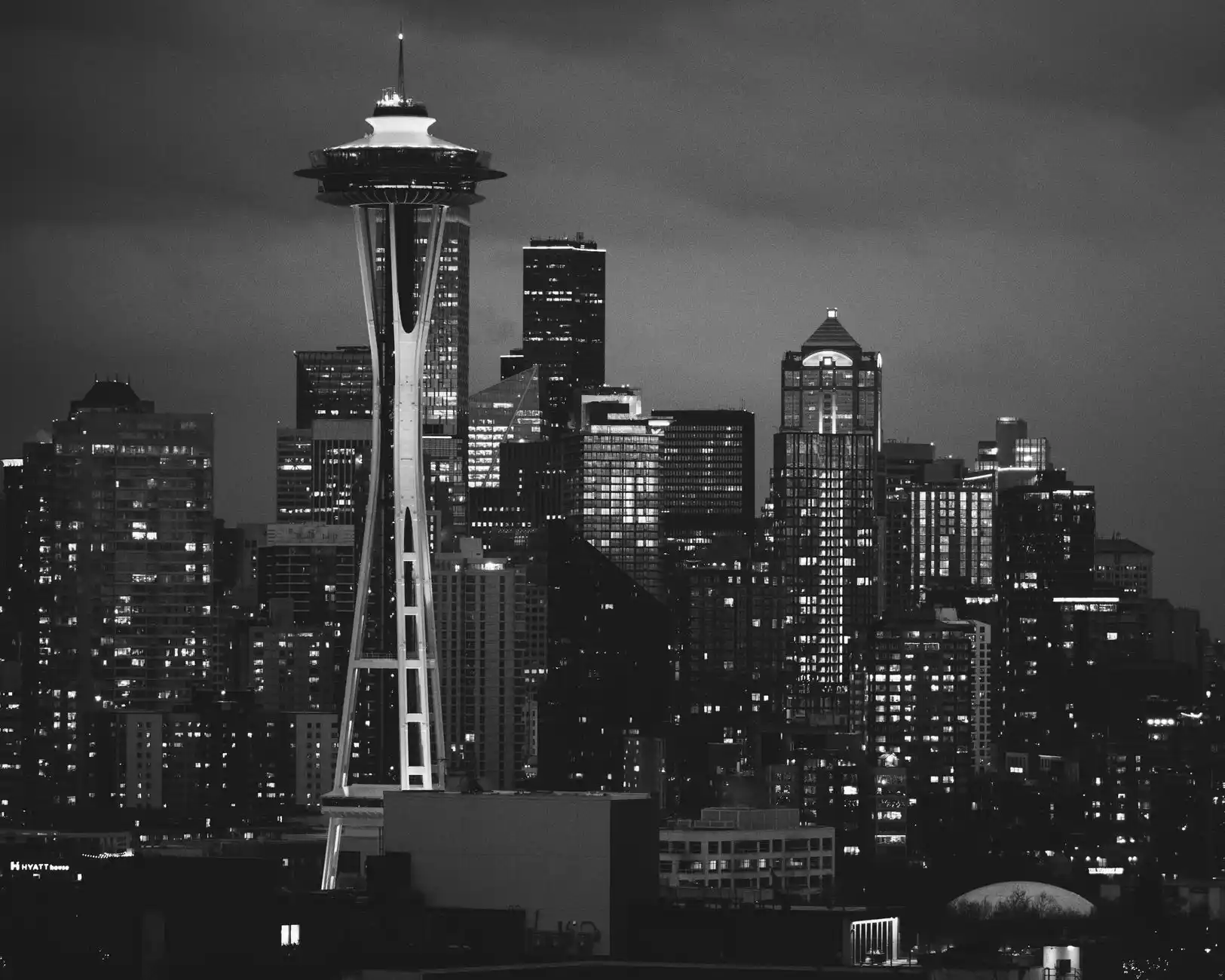 elegant black town car driving through downtown Seattle at dusk with skyline lights, Space Needle in the background, chauffeur visible through windshield, light rain creating ci...