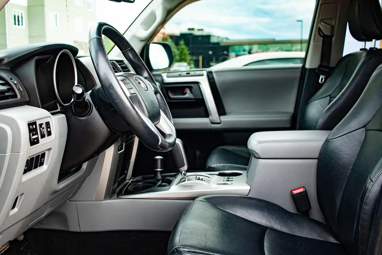 detailed interior of a premium black SUV with tan leather captain seats, bottled water, soft ambient lighting, tinted windows, and a city skyline visible through the windshield