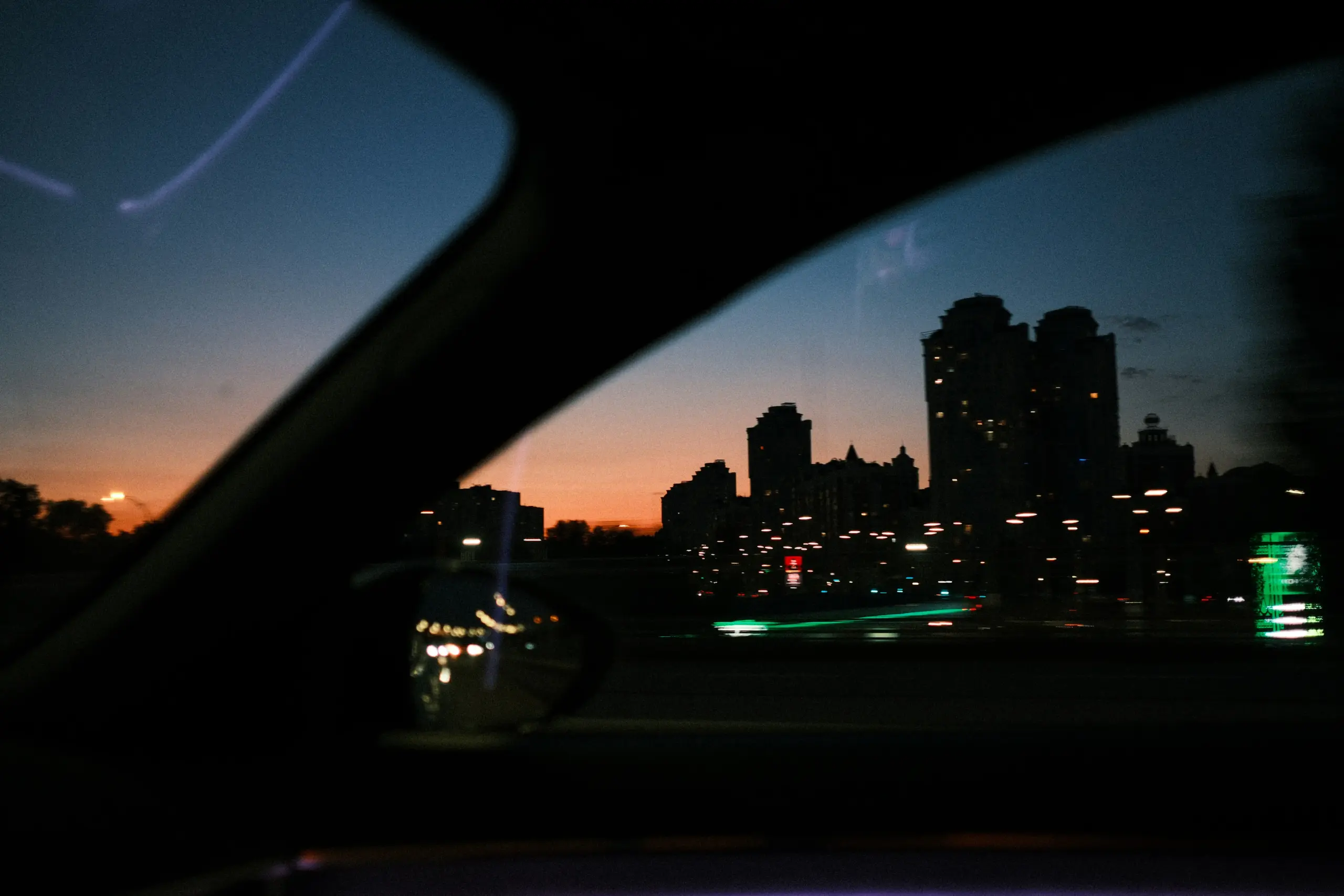 upscale SUV interior with spacious leather rear seating, bottled water, privacy-tinted windows, laptop bag and briefcase neatly placed, city skyline visible through windshield