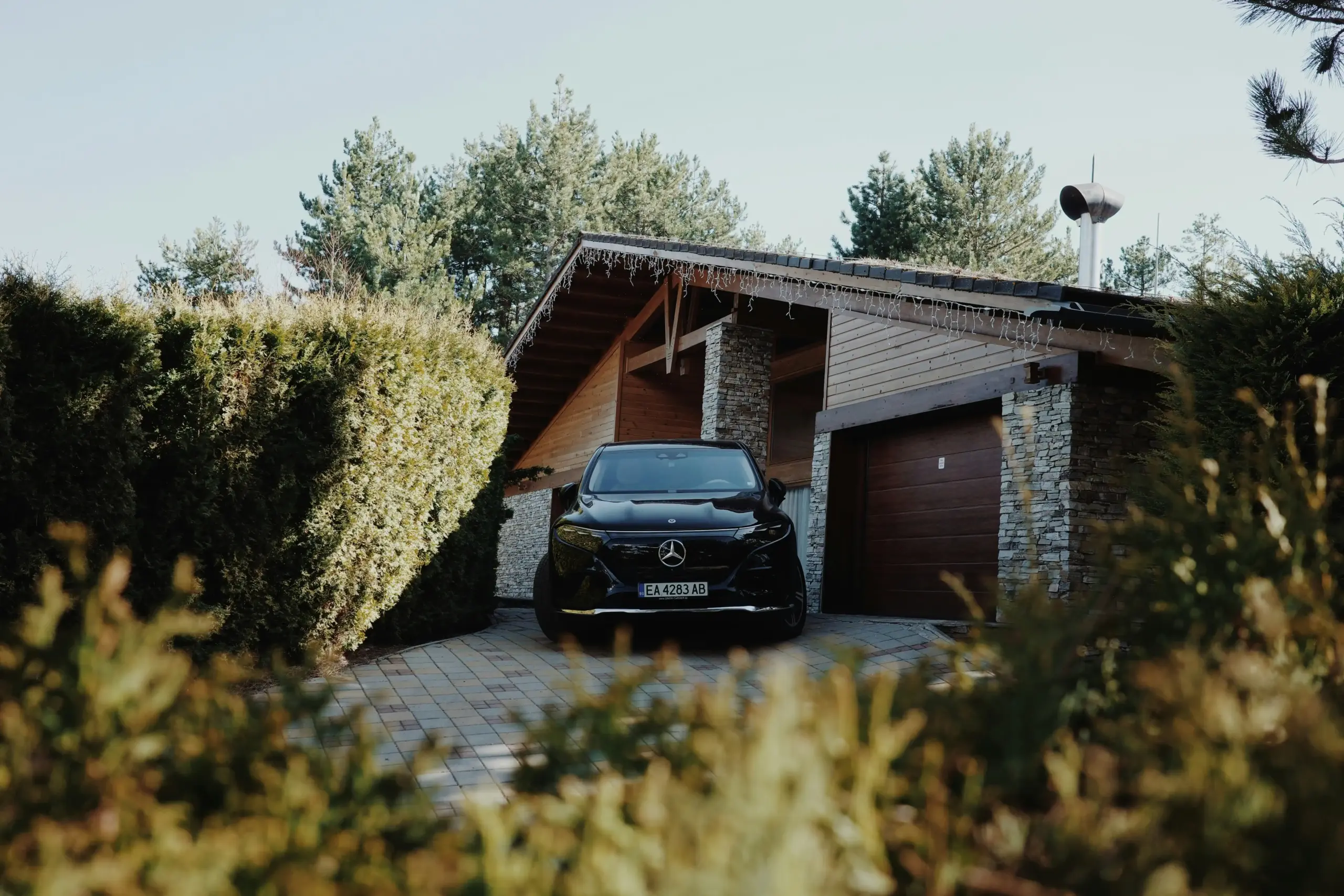 black luxury SUV parked at a modern Seattle home driveway at dawn, professional chauffeur opening rear passenger door, luggage ready for airport transfer, clean upscale suburban...