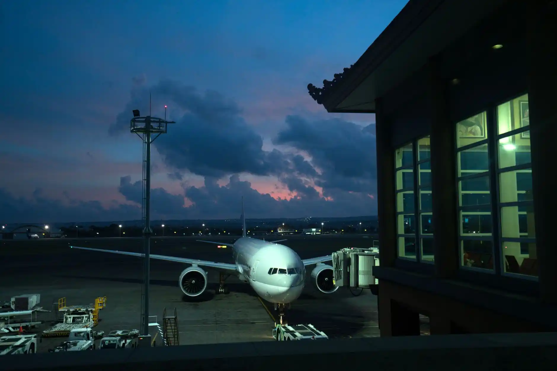 black luxury sedan at SeaTac airport arrivals curb at dusk, chauffeur opening rear door, travelers with rolling luggage, clean modern airport lighting, realistic upscale travel ...