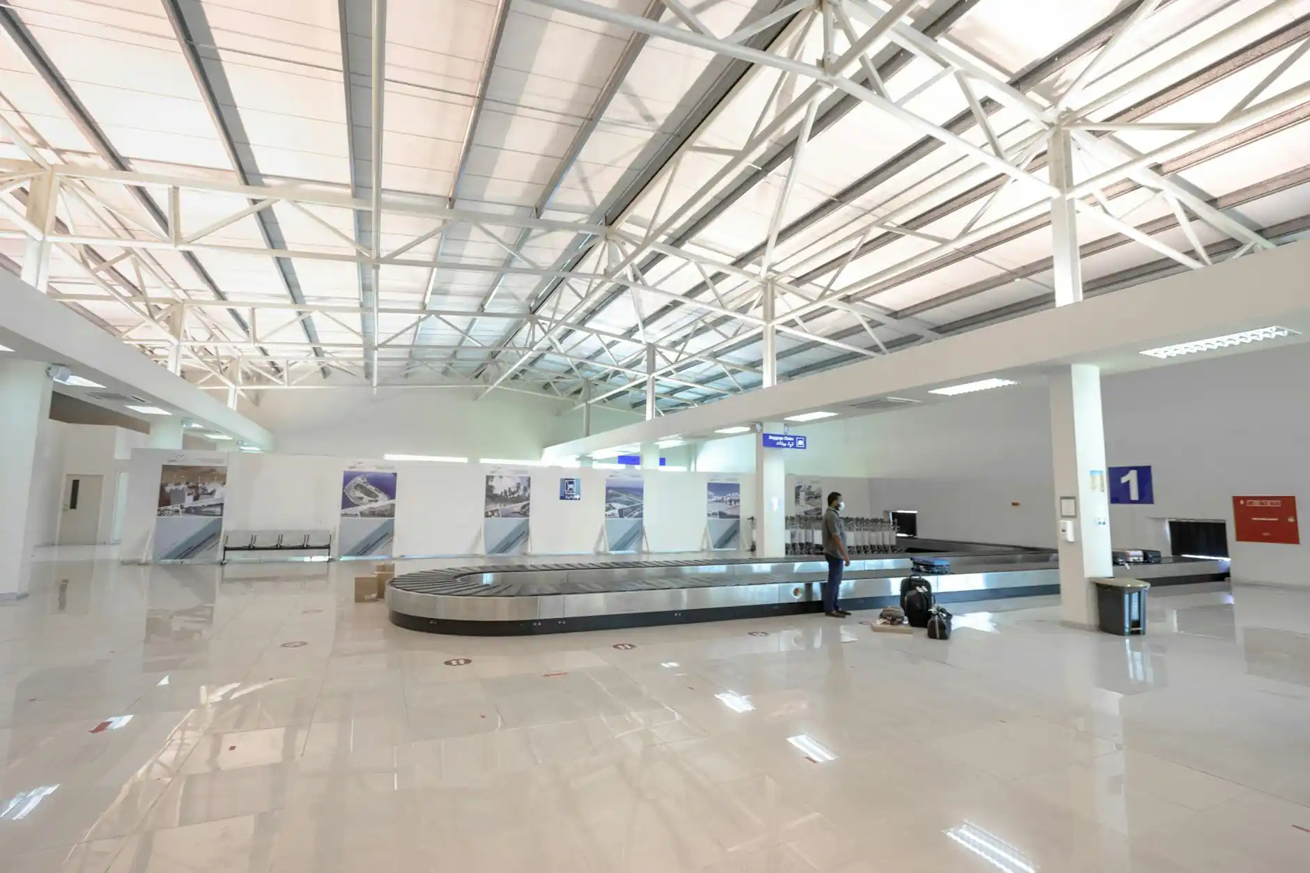 chauffeur assisting a family with luggage and stroller at Sea-Tac baggage claim, warm terminal lighting, clear signage, luxury SUV visible through sliding doors outside
