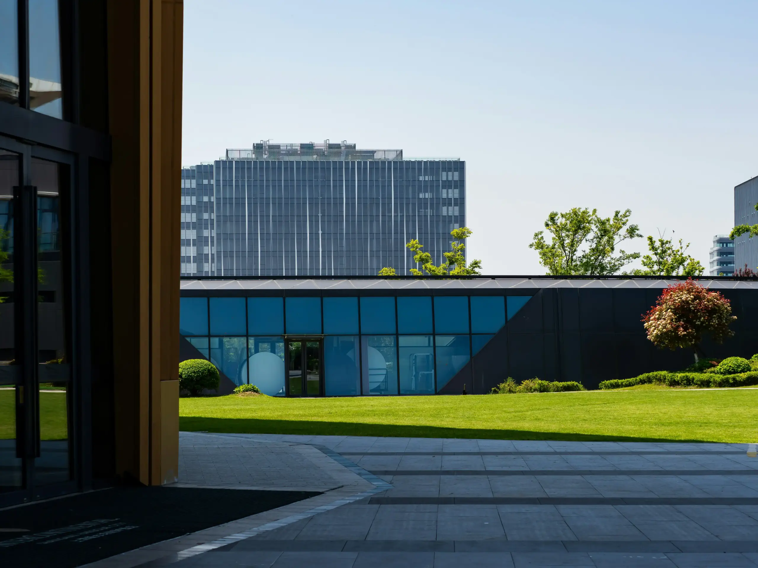 Black executive sedan waiting outside a modern Kirkland office building, uniformed chauffeur holding the rear door, Lake Washington visible in the background