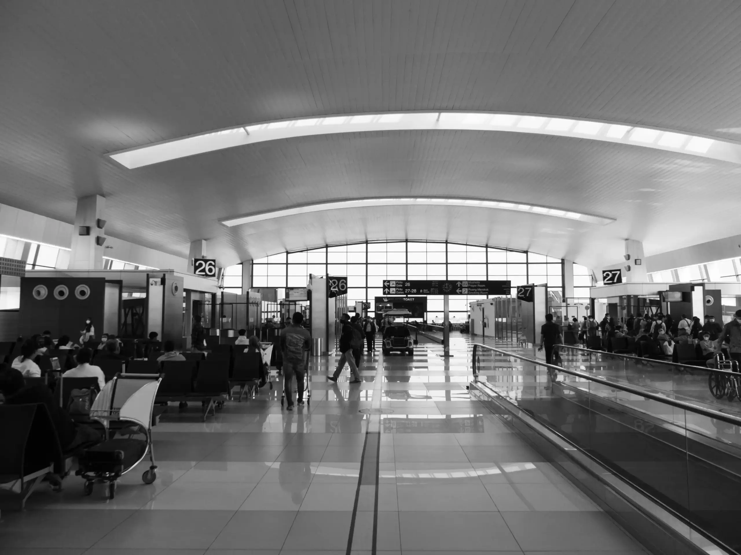 Black luxury town car waiting outside Seattle-Tacoma International Airport arrivals, professional chauffeur beside the rear door, evening terminal lights, realistic editorial ph...